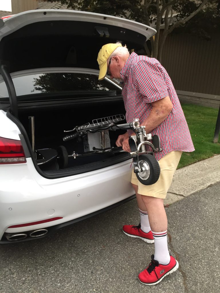 A man loading his mobility scooter into his cars trunk