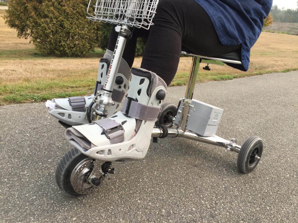A woman wearing Charcot Restraint Orthotic Walker riding a 3-wheel mobility scooter canada