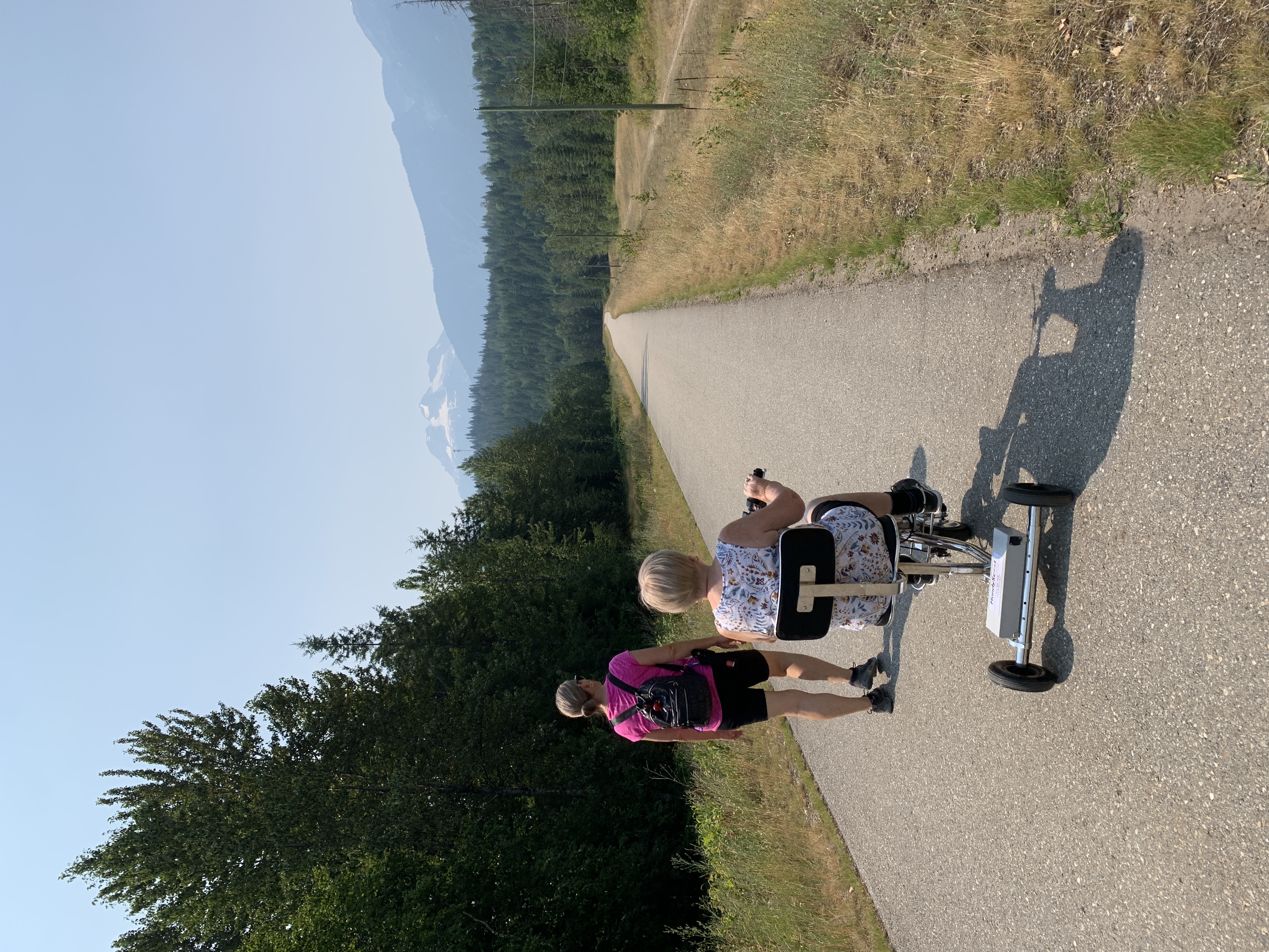 A woman riding a 3 wheel mobility scooter going for a ride with her daughter